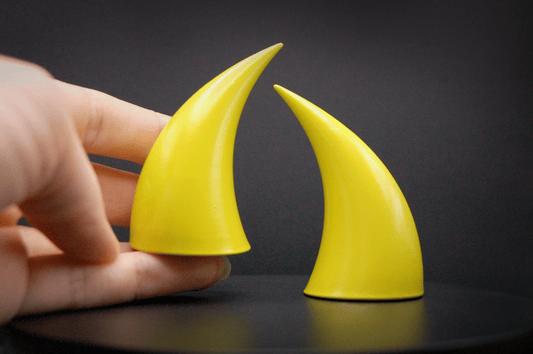 Hand holding an incubus devil horn in sulfur yellow with a glossy finish.