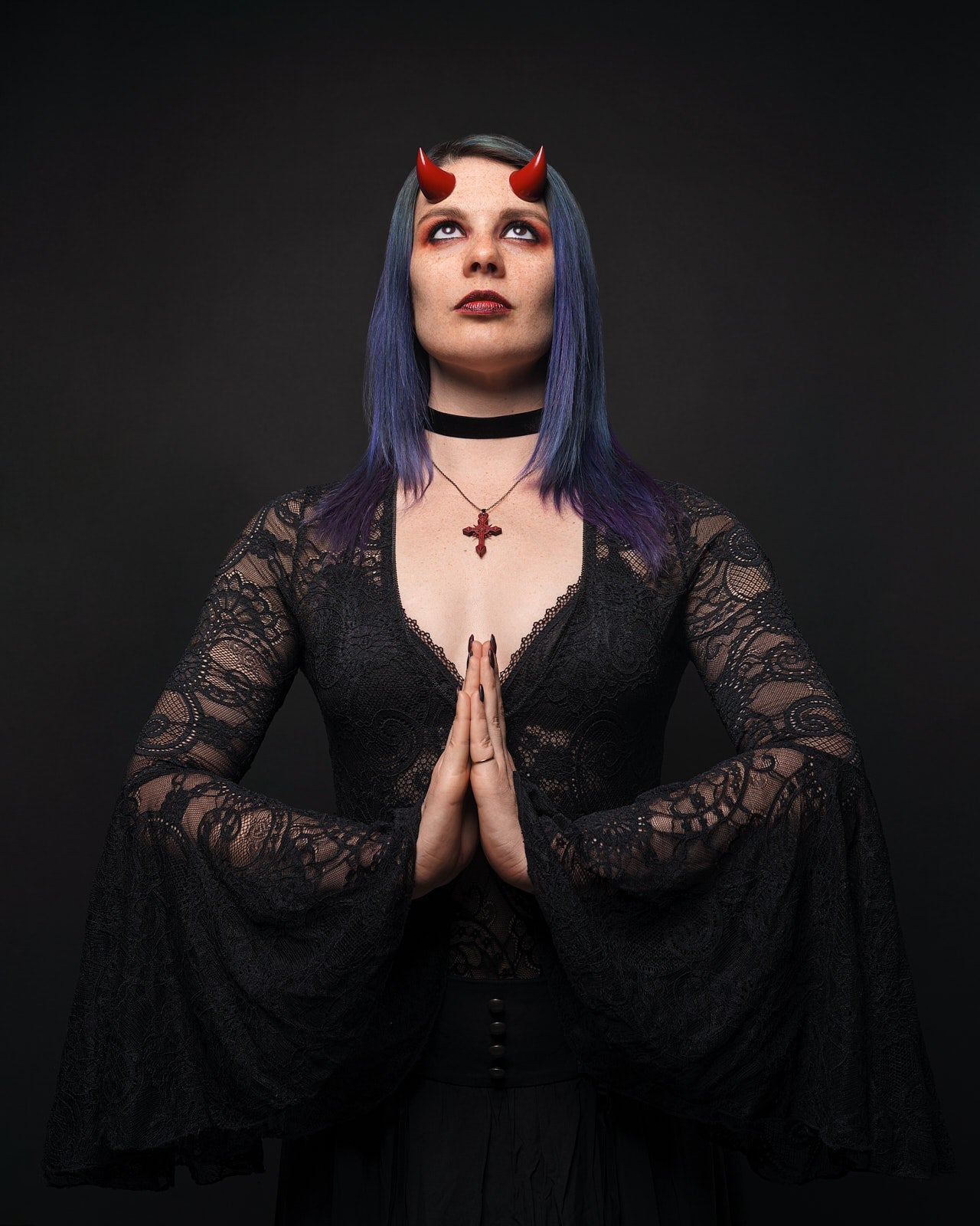 Model Splitty Kitty poses in gothic attire wearing bordeaux red imp horns on her forehead. Photo by Brian Keyes.