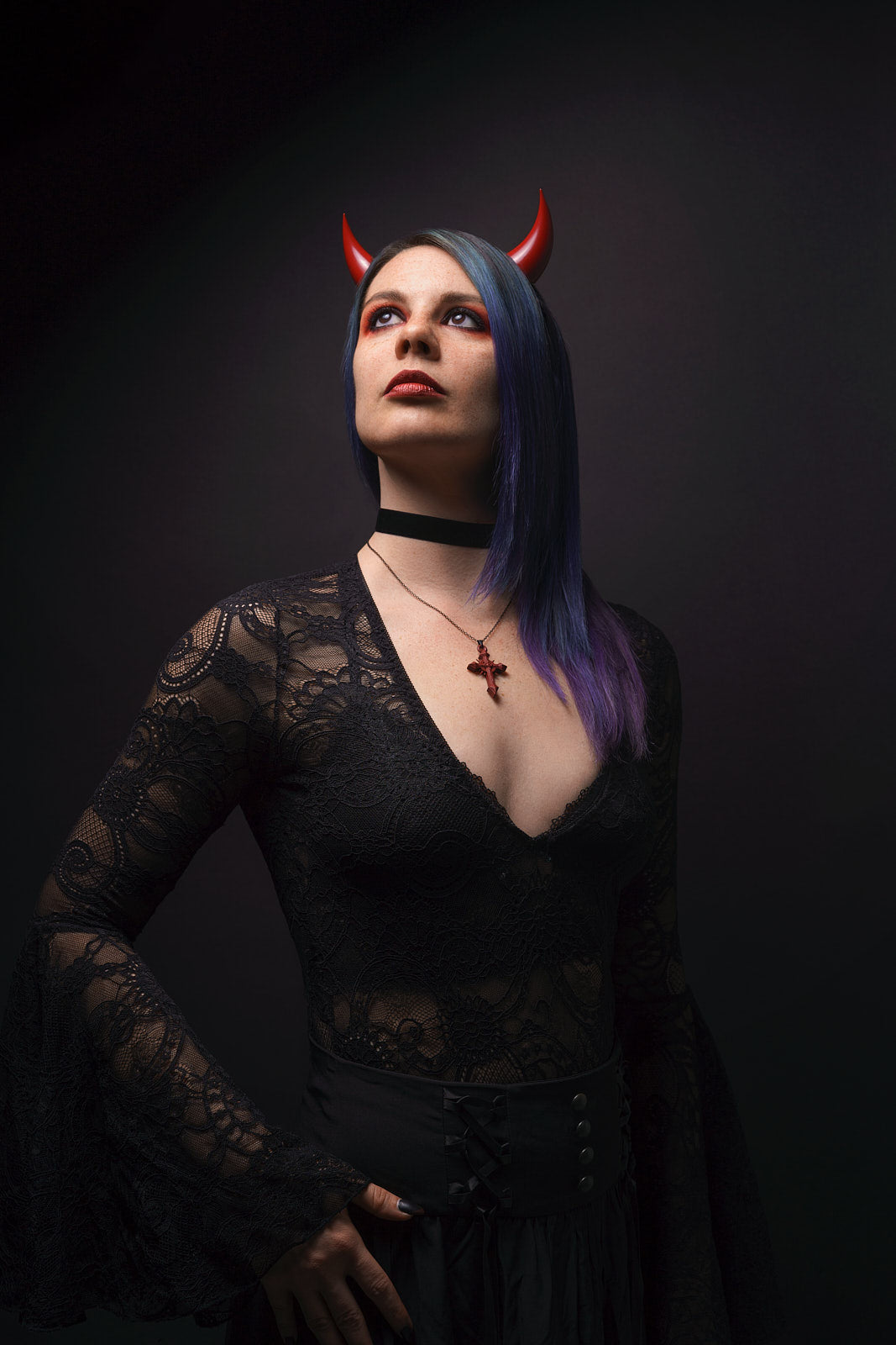 Model Splitty Kitty poses in gothic attire wearing bordeaux red incubus horns on her forehead. Photo by Brian Keyes.