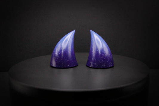 Front view of imp devil horns in a royal purple to periwinkle ombré with a glittery finish.