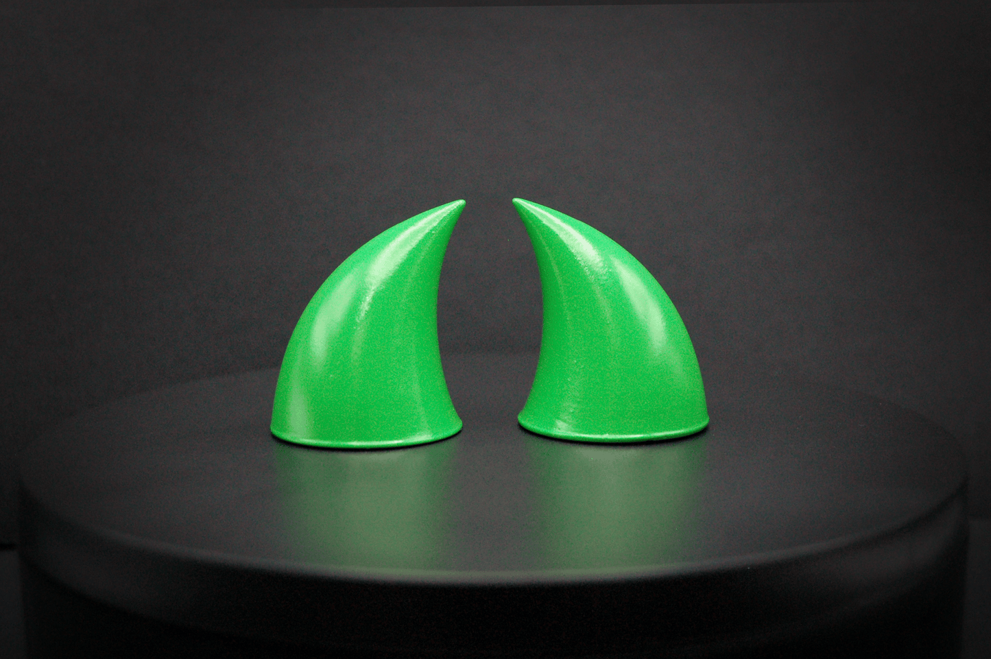 Front view of imp devil horns in goblin green, a bright green with a glossy finish.