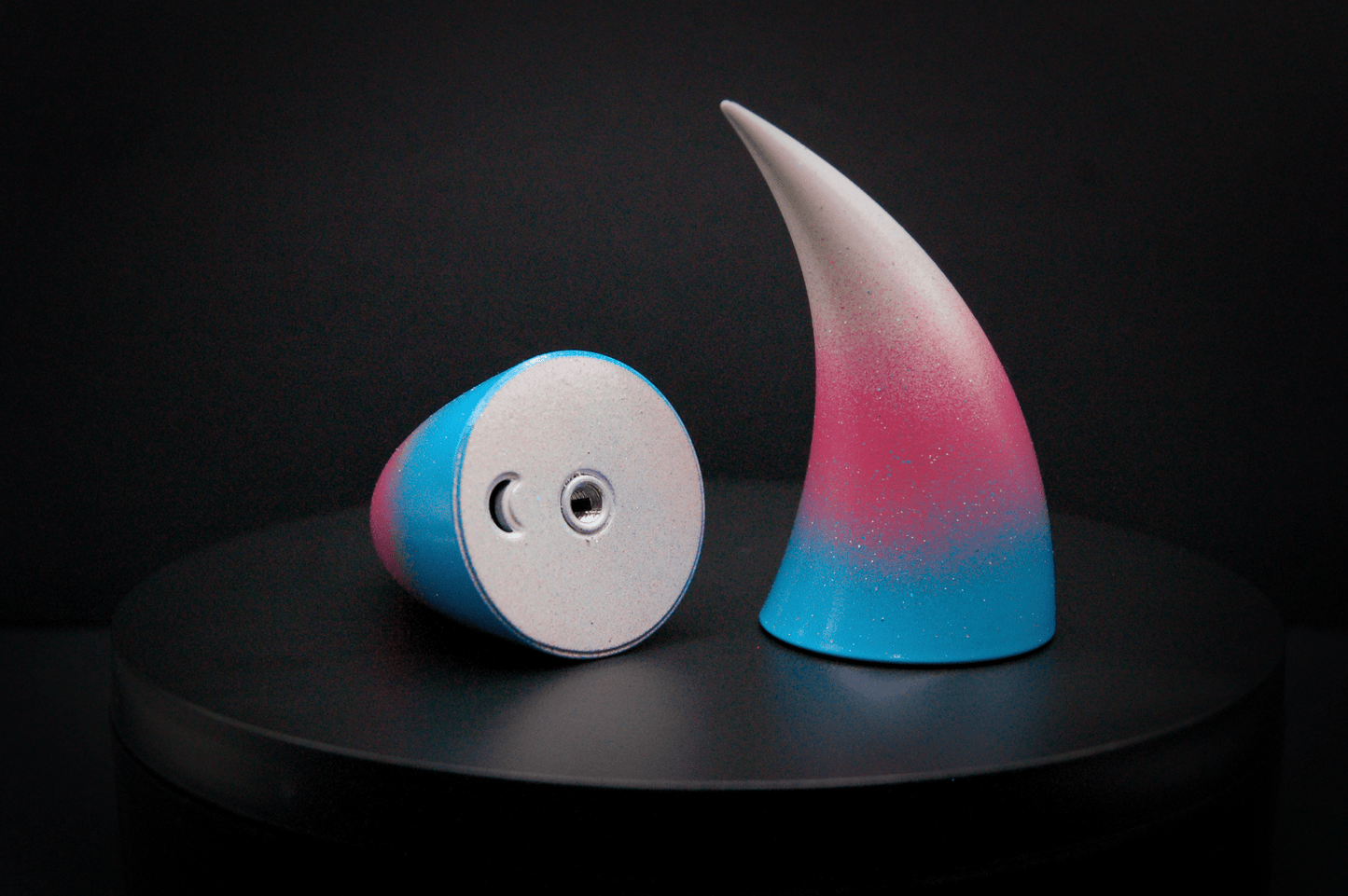 Bottom view of devil horns in a light blue, medium pink, and white ombré, the colors of the trans pride flag with a glittery finish, showing a threaded insert on the base.